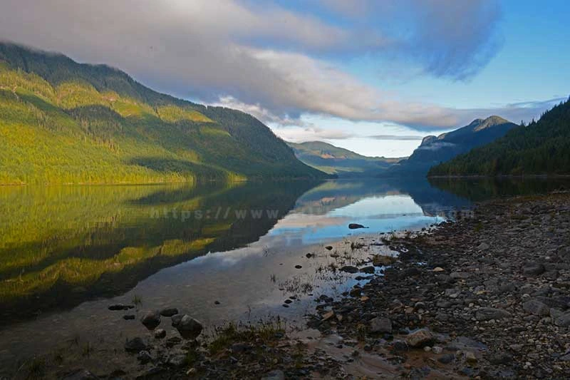 image of capturing the perfect reflection of a sunrise on the mountains and water on Bonanza Lake, Vancouver Island Canada