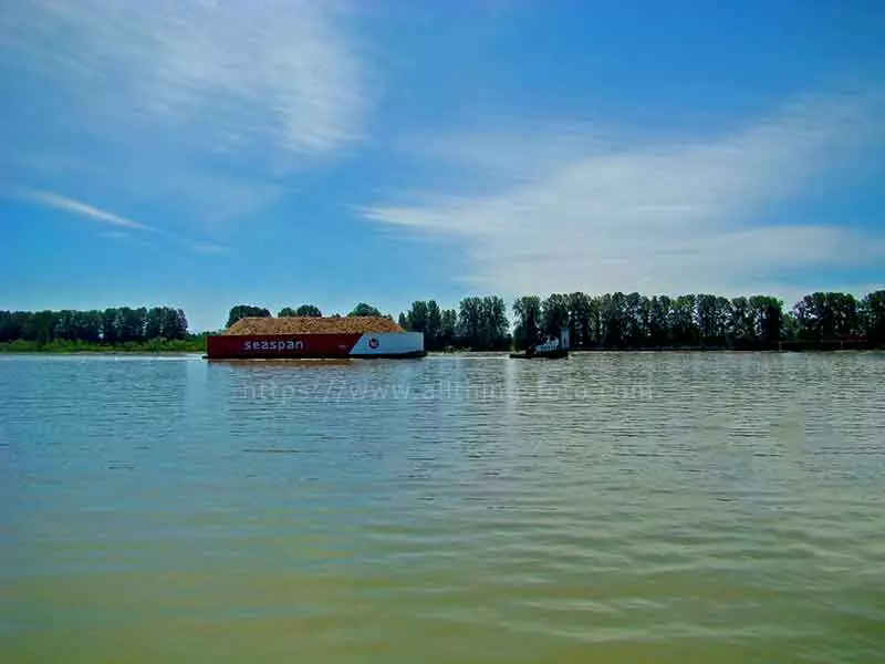 photo of a seaspan tug towing a barge of wood chips down the fraser river in bc canada