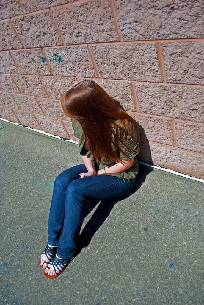 photo of a young girl looking down the sidewalk along the wall